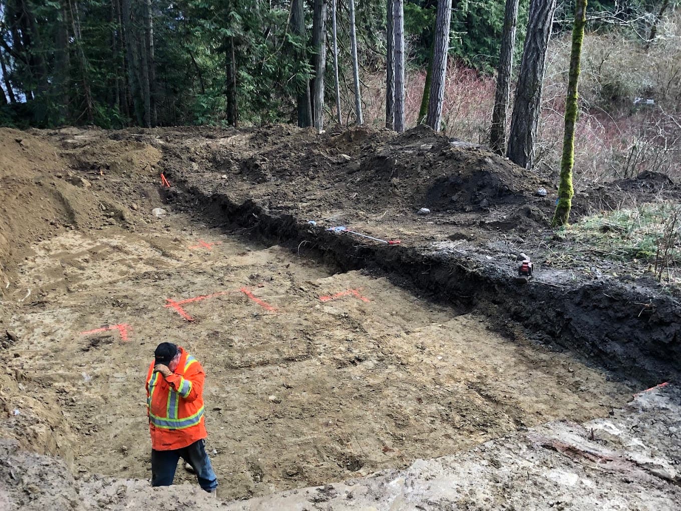 A worker in hi-vis on a marked-out building pad with survey paint on the ground